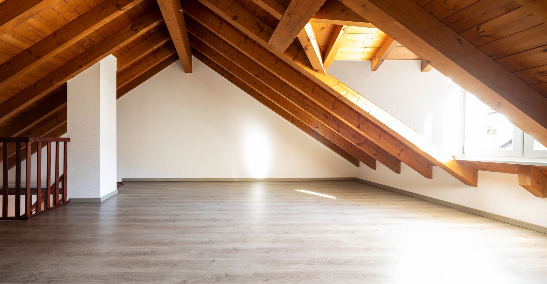 Finished attic conversion with exposed A-frame beams and wood-look flooring