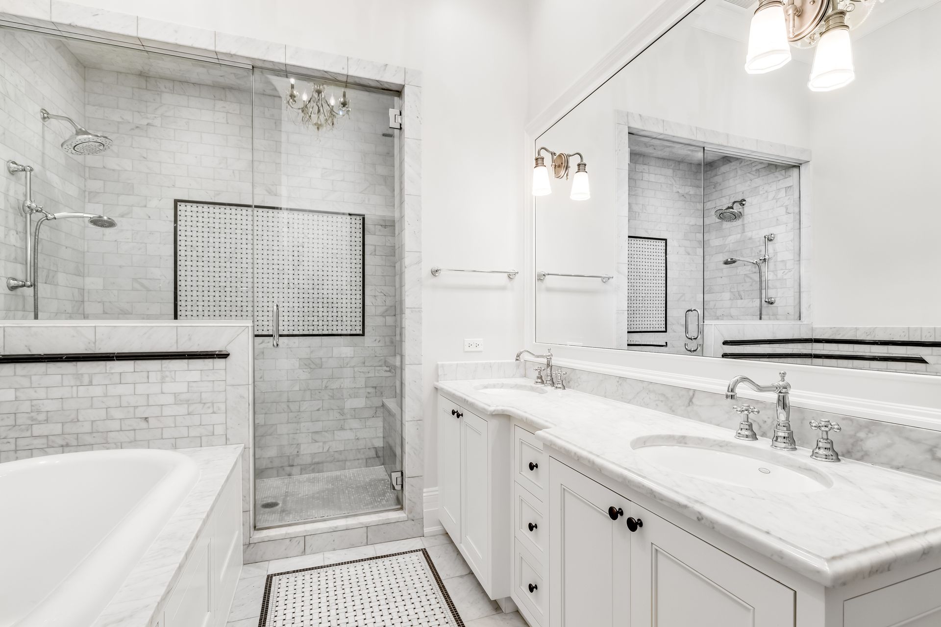 Remodeled bathroom with a glass walk-in shower, marble tile and a freestanding tub