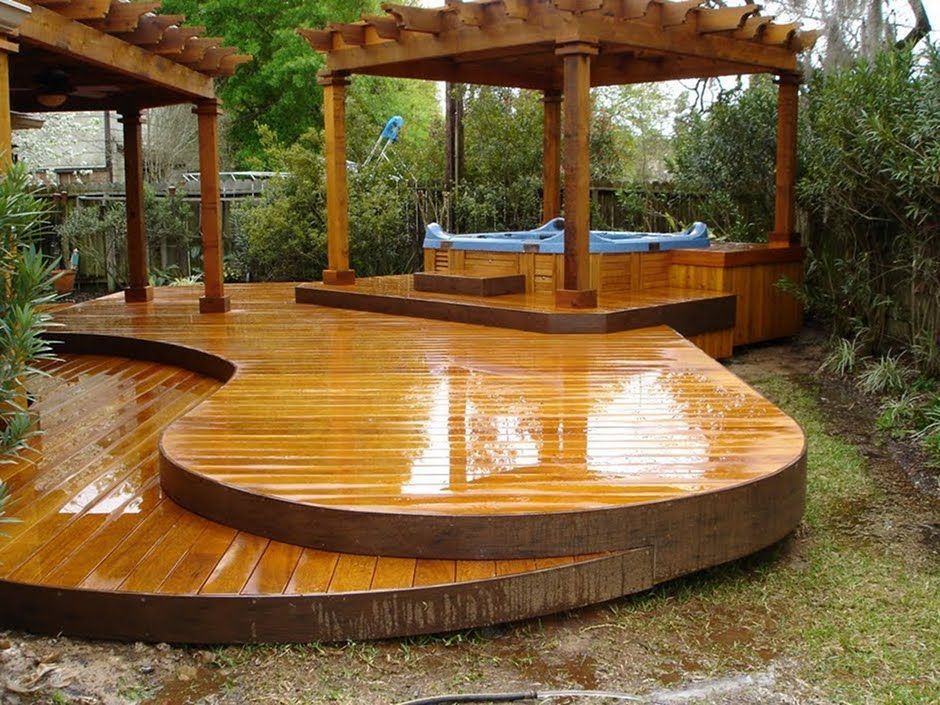Stained wood deck with railings overlooking a leafy backyard