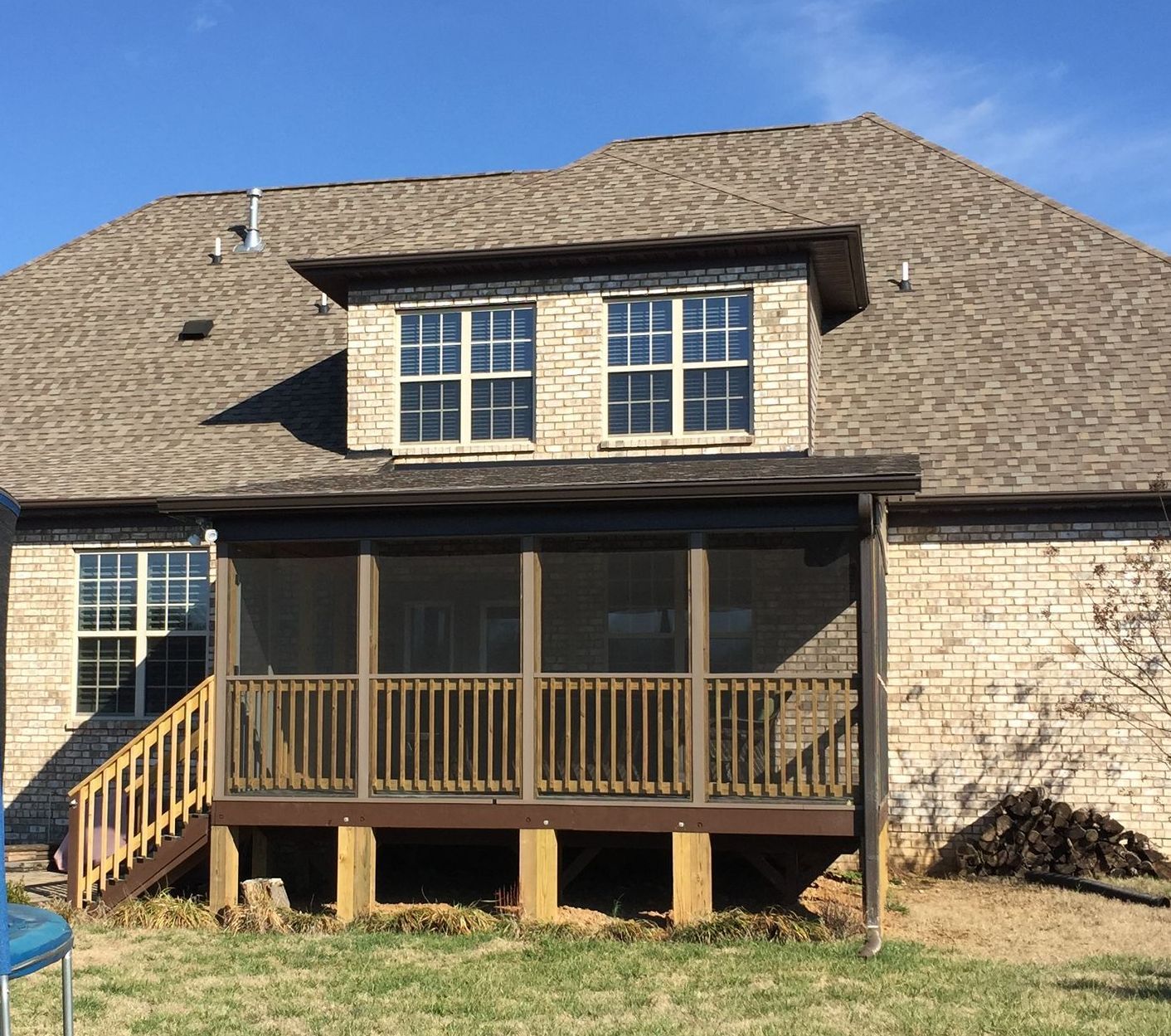 Screened porch and covered deck built onto the rear of a two-storey brick home