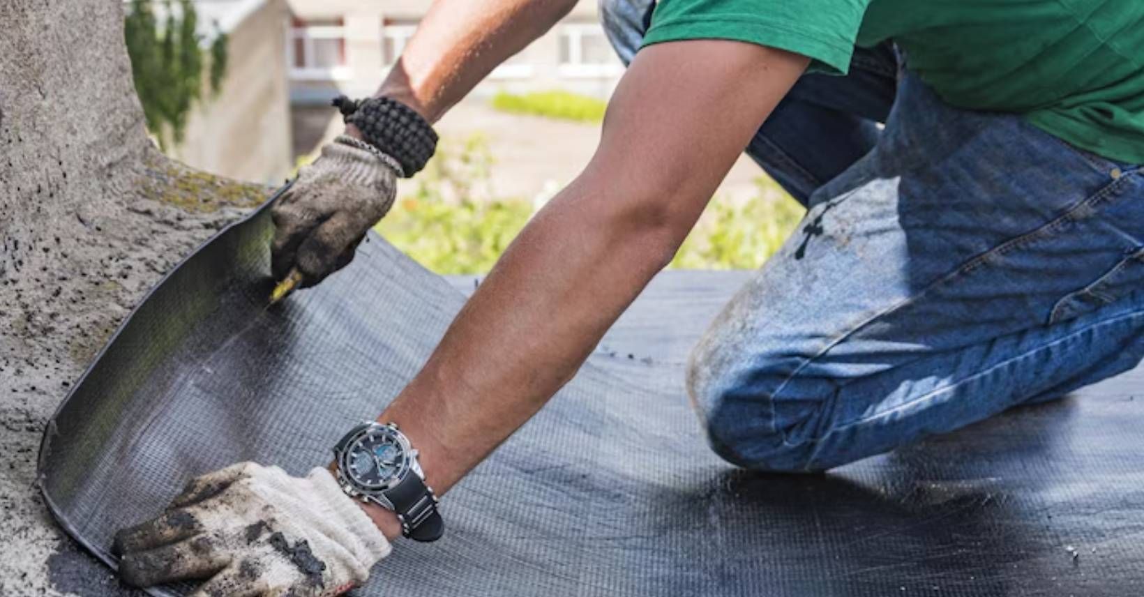Worker laying a black waterproofing membrane sheet over a surface